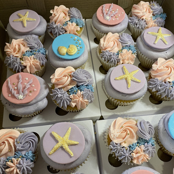 Decorative cupcakes with starfish and floral designs in pastel colors.